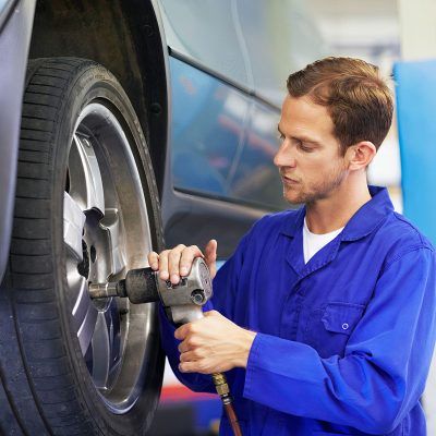 A mechanic torquing the lug nuts of a wheel with a wrench