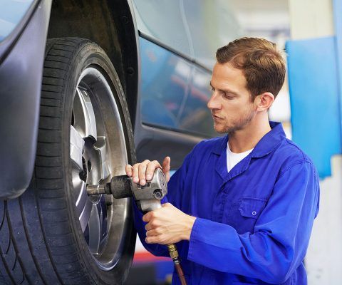 A mechanic torquing the lug nuts of a wheel with a wrench